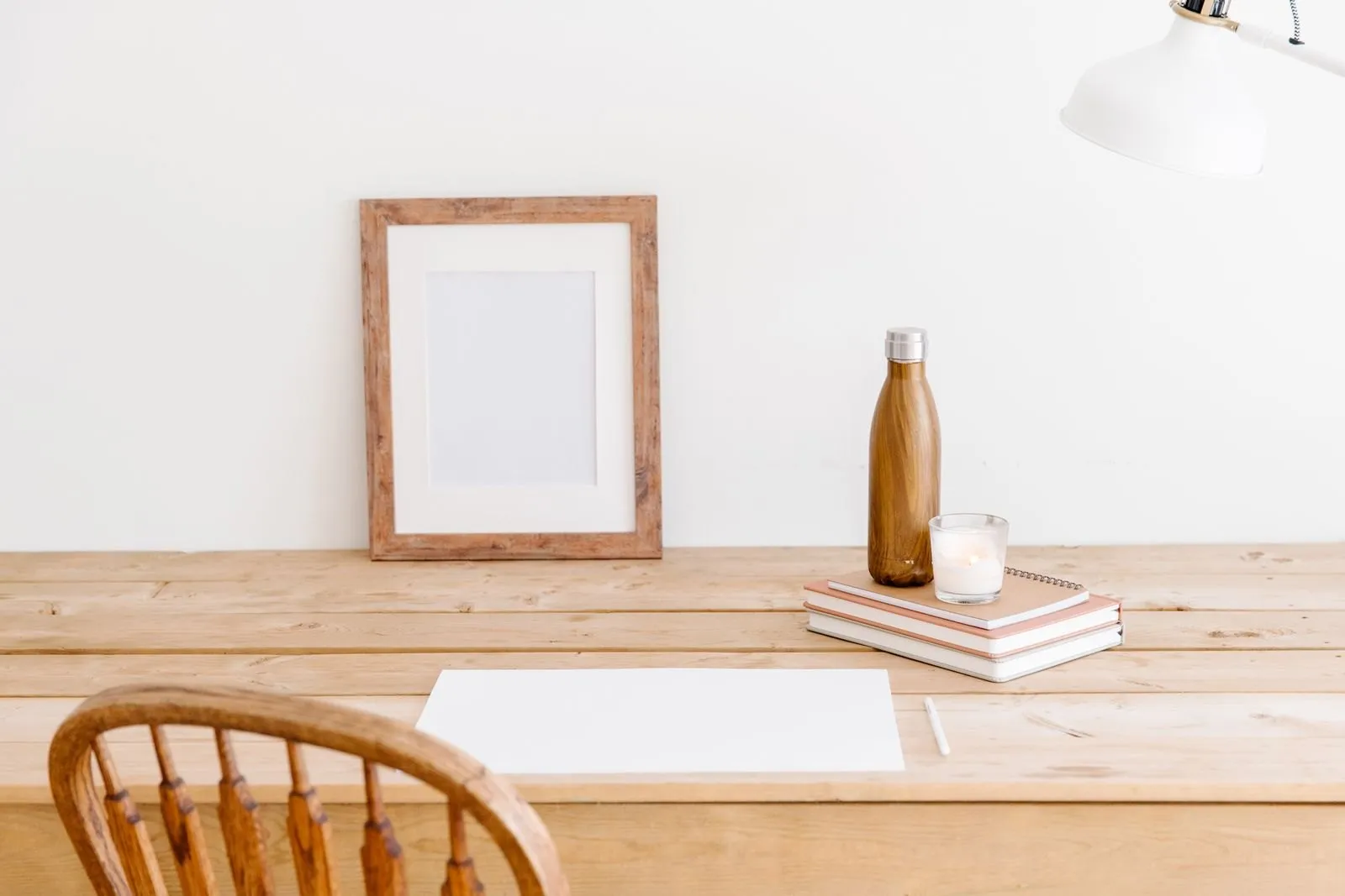 A steel bottle on a stack of notebooks on a light wooden desk