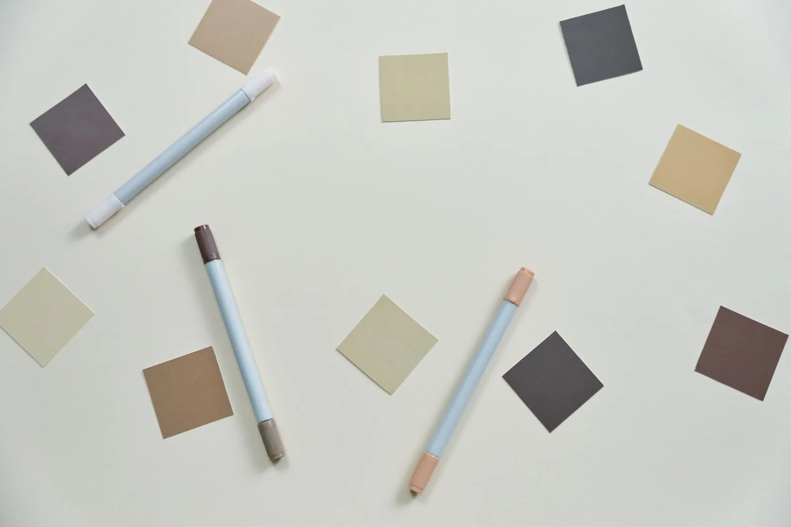 Pastel markers and sticky notes on a cream surface