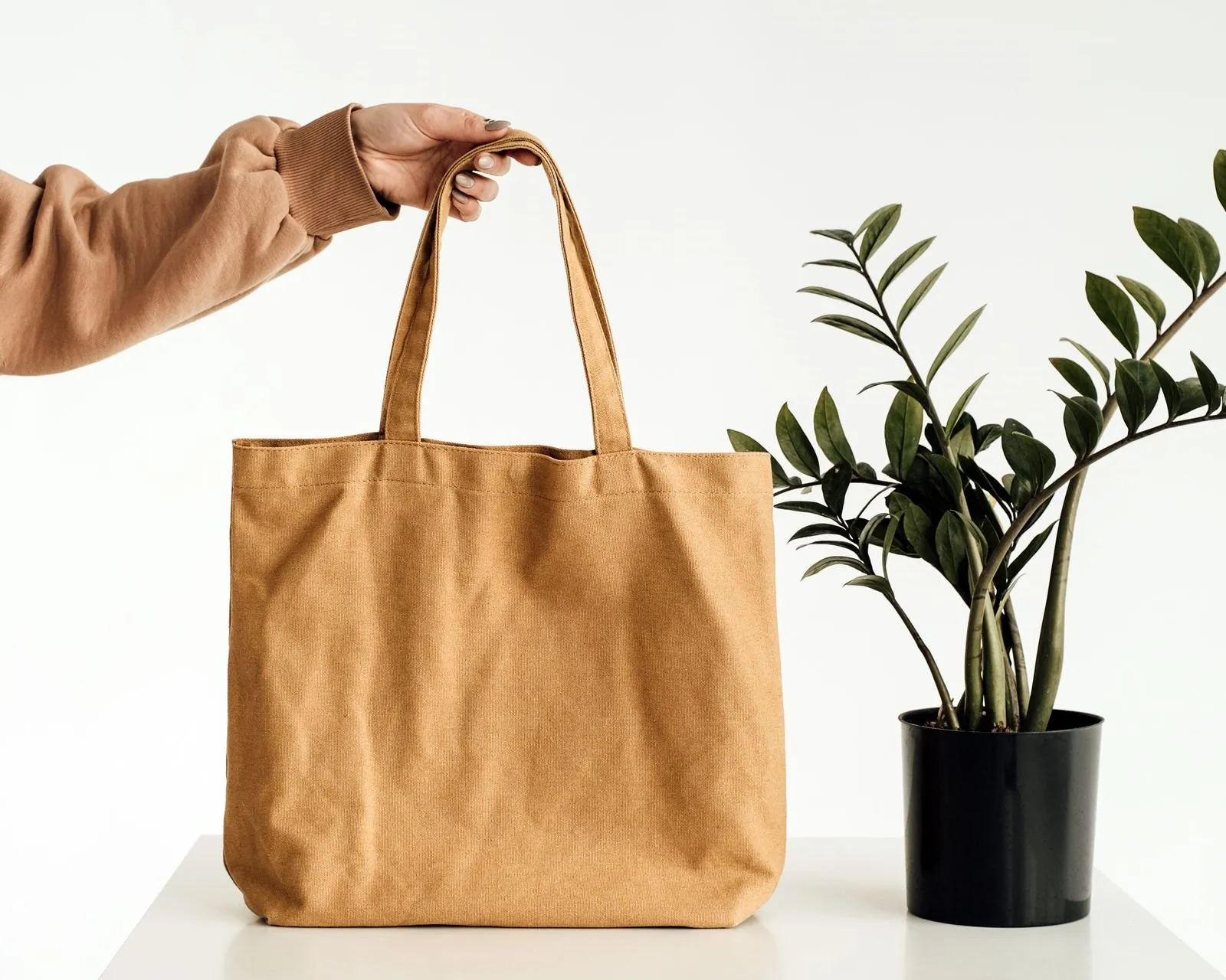 A tan canvas tote bag on a white block