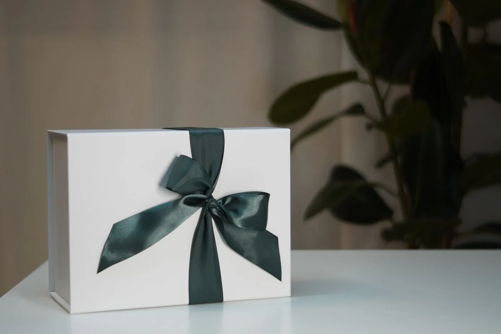 A white gift box tied with a green satin bow
