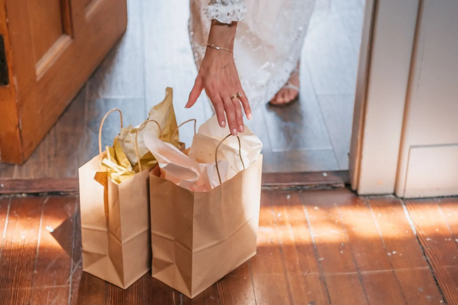 Two kraft gift bags filled with tissue paper on a sunlit floor